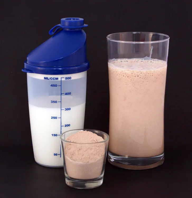 Coctelera con leche, proteína en polvo y un batido preparado